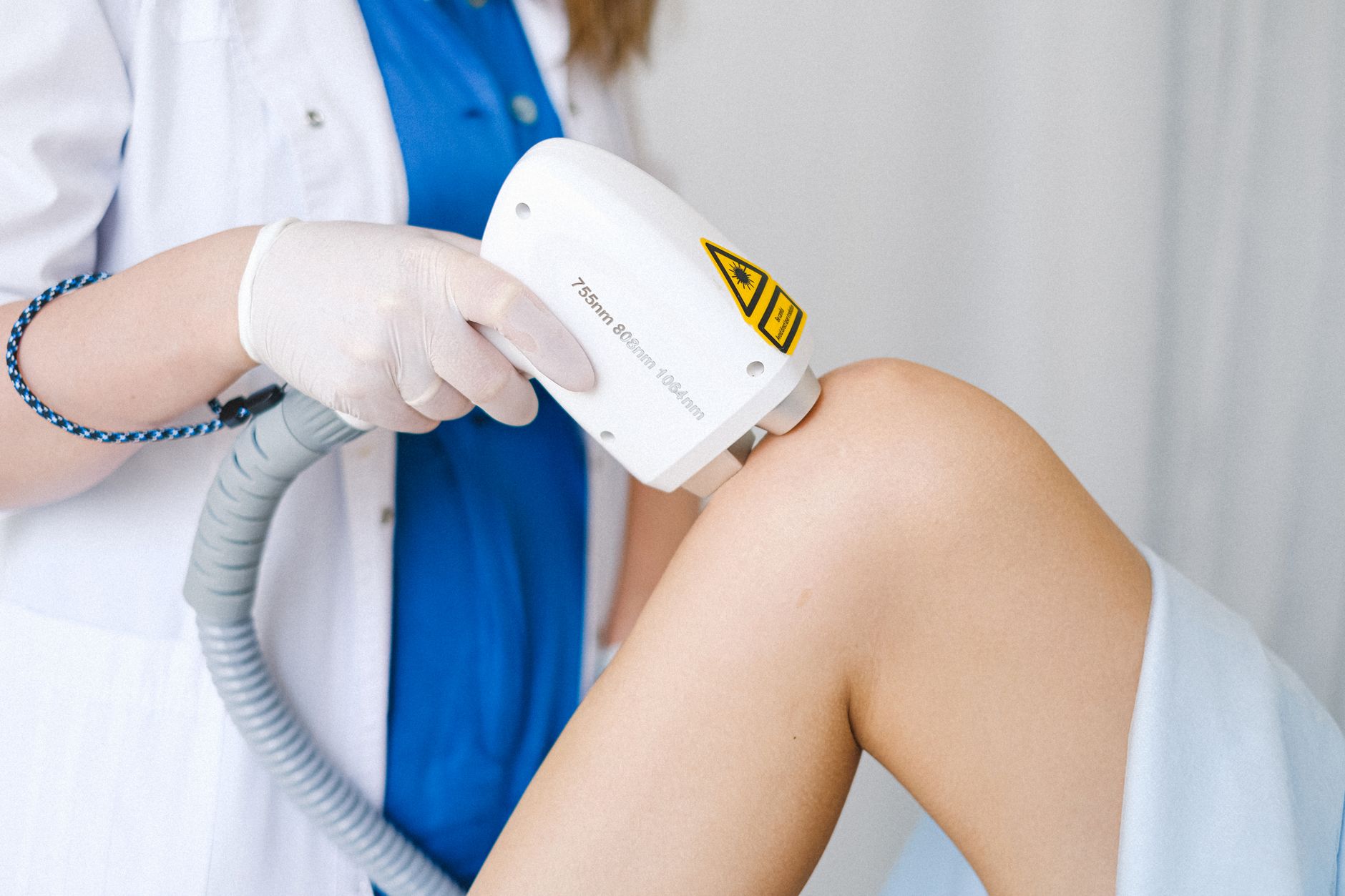 Aparelho de depilação a laser aplicado no joelho, em ambiente clínico