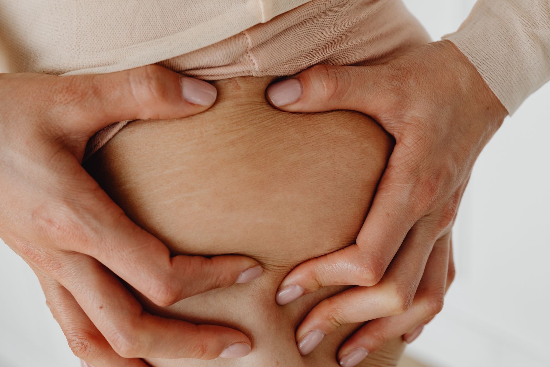 Mãos apoiadas sobre a barriga, mostrando a textura da pele