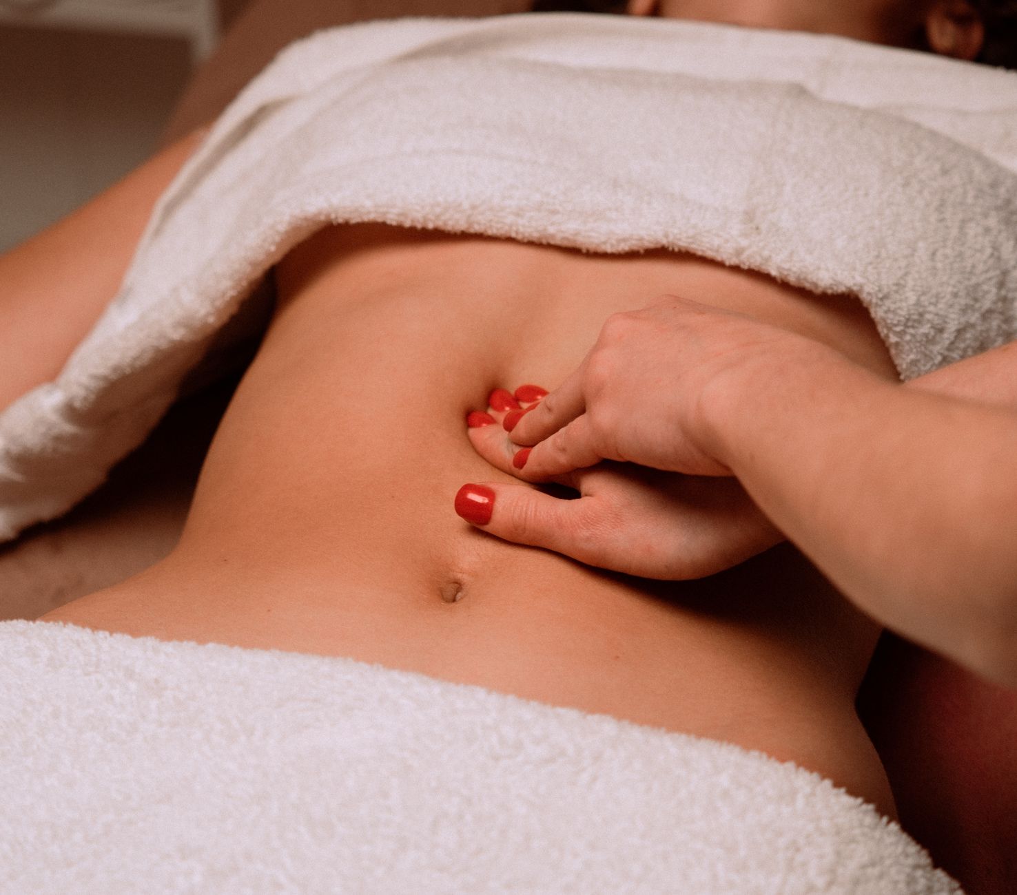 Sessão de drenagem linfática abdominal, com a cliente sob toalha