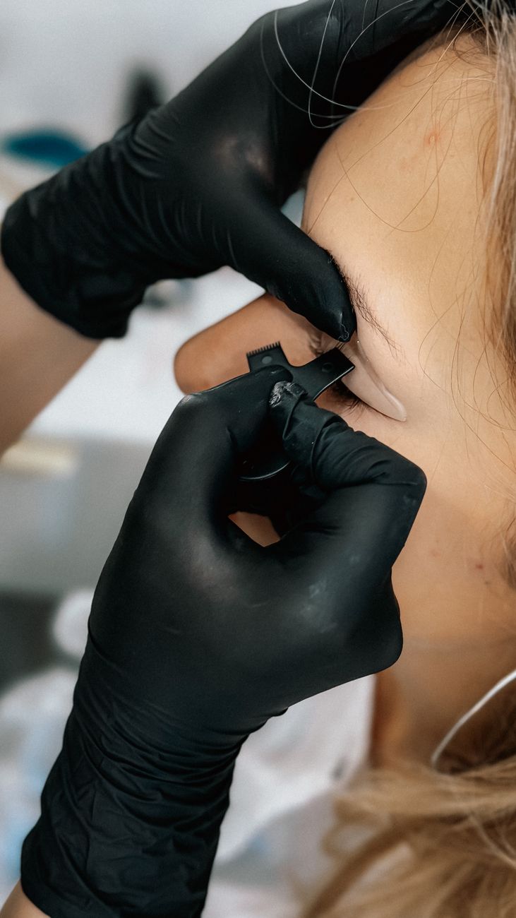 Profissional de luvas desenhando a sobrancelha com régua de medição